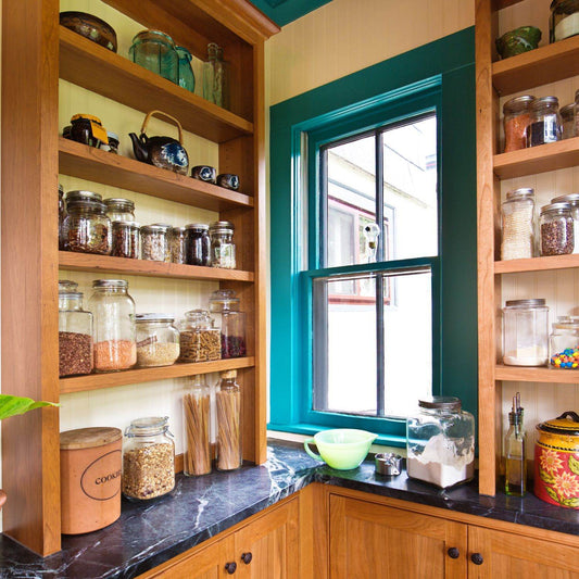 Organized kitchen shelves with jars of herbs and grains for spring herbal pantry essentials