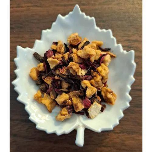 Apple Chai tea leaves in a white leaf-shaped bowl on a wooden surface