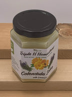 Jar of Triple H Homestead Calendula Salve with Lavender on a wooden surface
