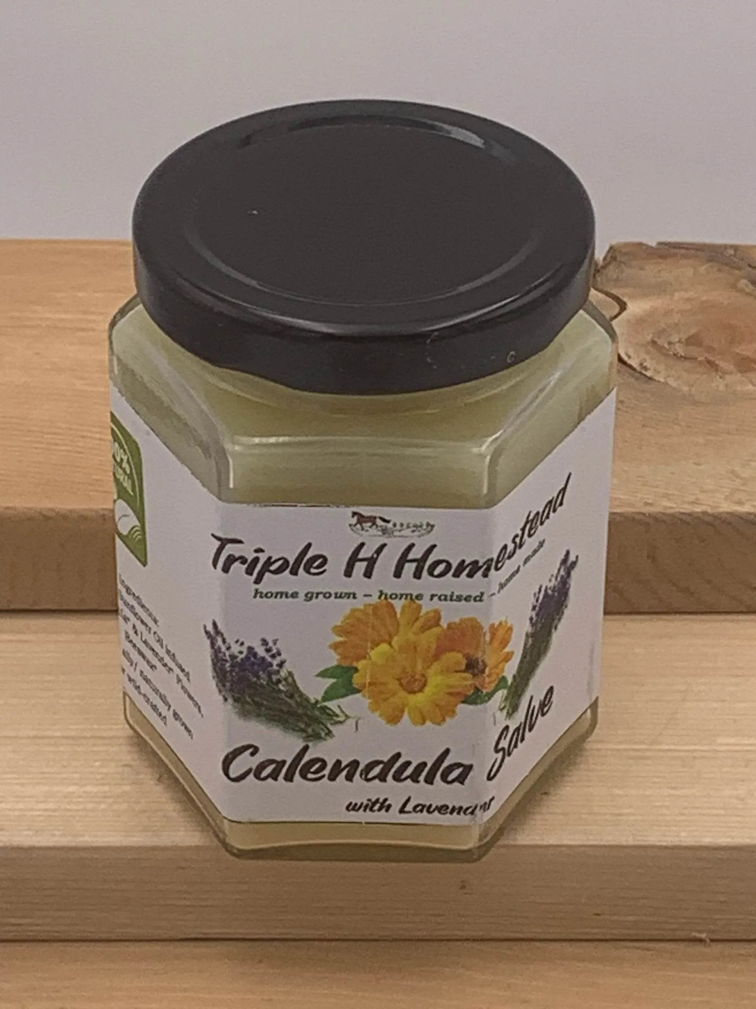 Jar of Triple H Homestead Calendula Salve with Lavender on a wooden surface