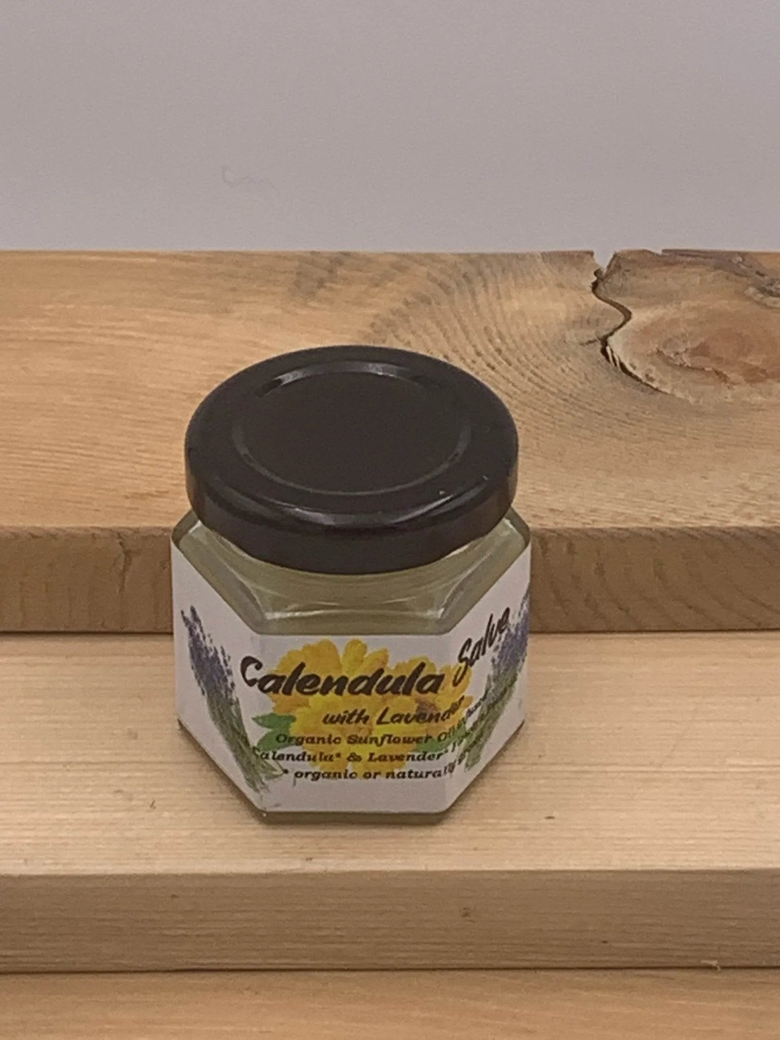 Jar of calendula salve with lavender on a wooden surface
