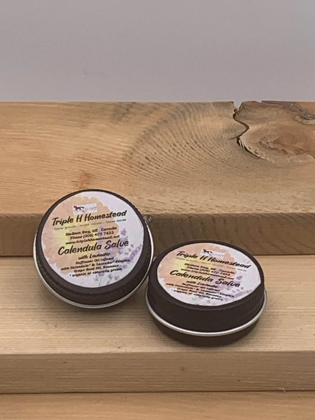 Two containers of Calendula Salve on a wooden surface with a neutral background