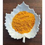 Carrot Cake Latte powder in a white leaf-shaped container on a wooden surface