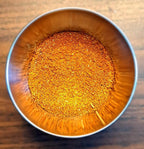 Metal bowl filled with a spice mix on a wooden surface