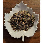 Cough Relief Tea herbs on a white leaf-shaped dish on a wooden surface