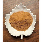Dandelion Mocha Latte powder in a white leaf-shaped container on a wooden surface