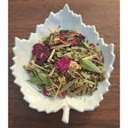 Detox & Cleanse tea mix in a white leaf-shaped bowl on a wooden surface