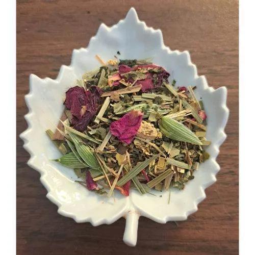 Detox & Cleanse tea mix in a white leaf-shaped bowl on a wooden surface