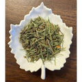 Diuretic Tea herbal blend on a white leaf shaped ceramic dish on a wooden surface.