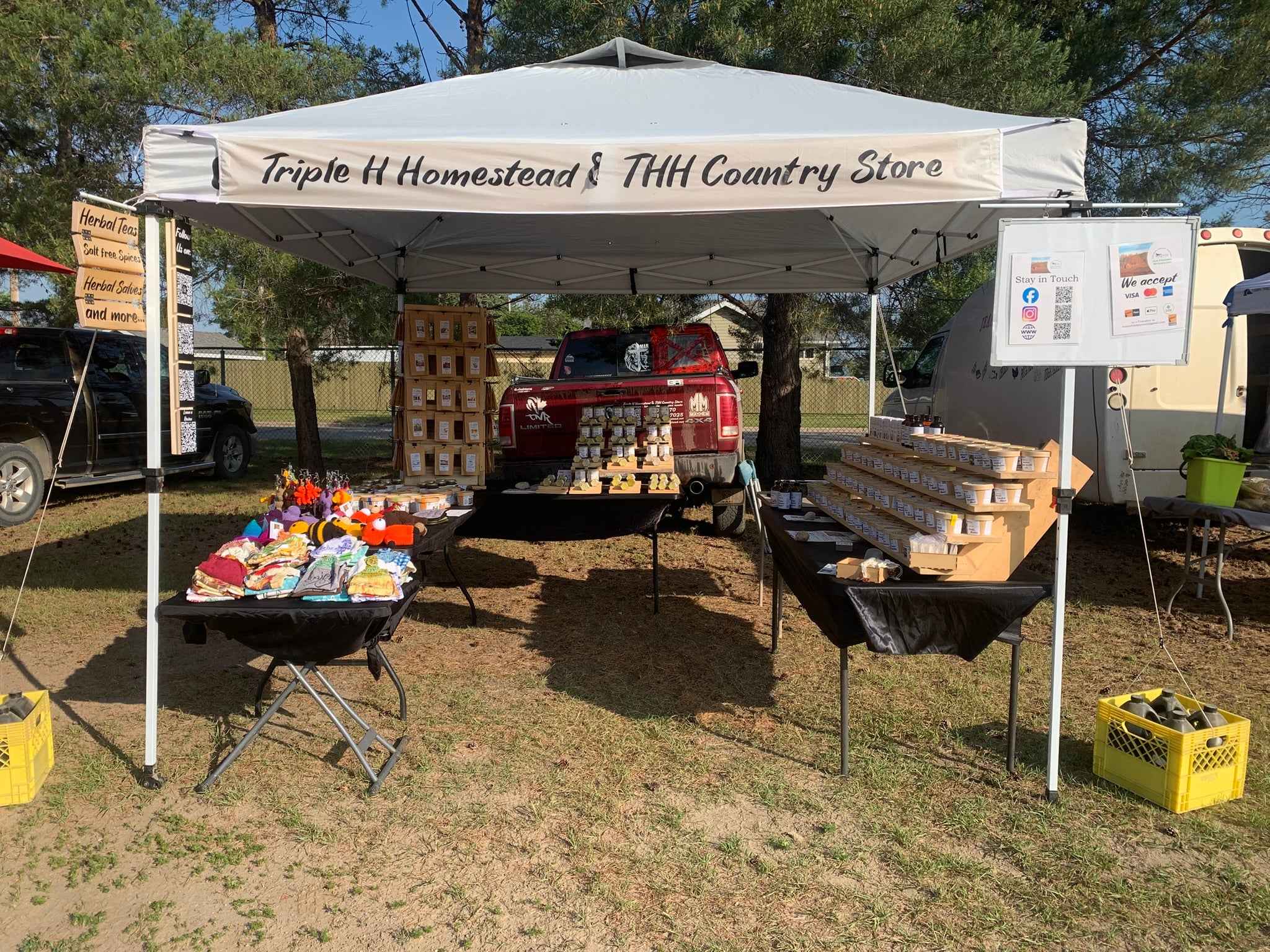Outdoor setup with a tent labeled 'Triple H Homestead & TTH Country Store' displaying various items.