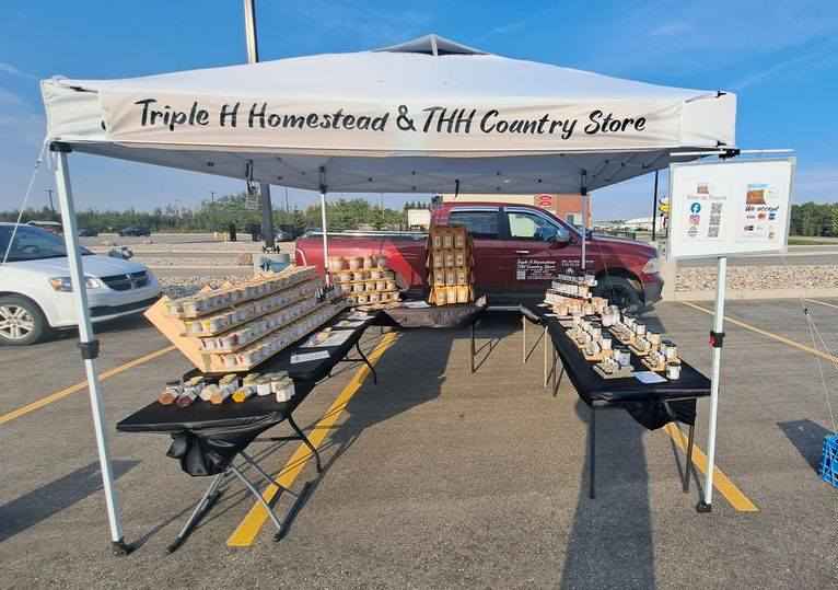 Outdoor setup with tables and products under a tent in a parking lot.