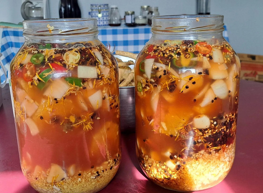 Two jars of fire cider on a table with a kitchen background.