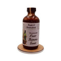 Amber glass bottle of 'Homemade Four Thieves Tonic' on a wooden coaster with a white background