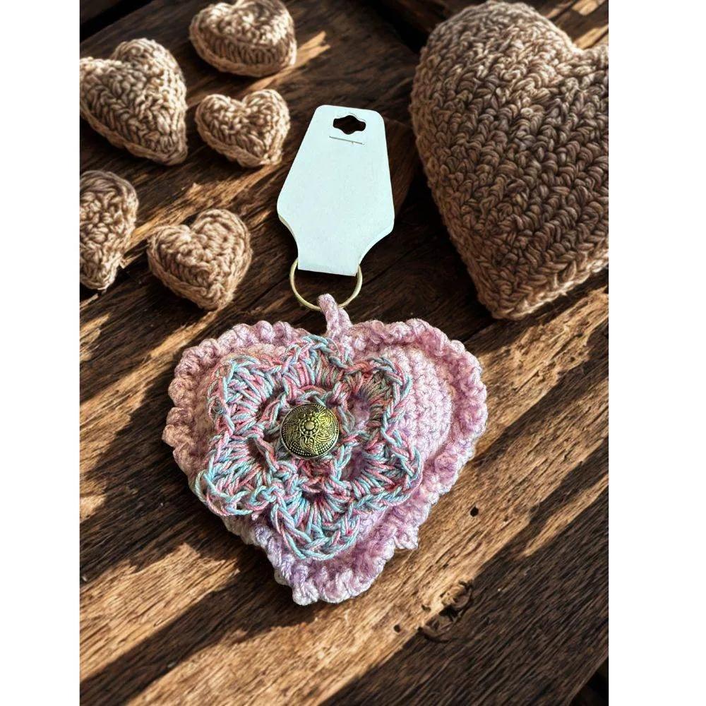 Crocheted heart-shaped keychain with a flower design on a wooden surface