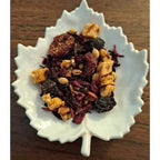 Homestead Fruit Chai herbs in a white leaf-shaped bowl on a wooden surface