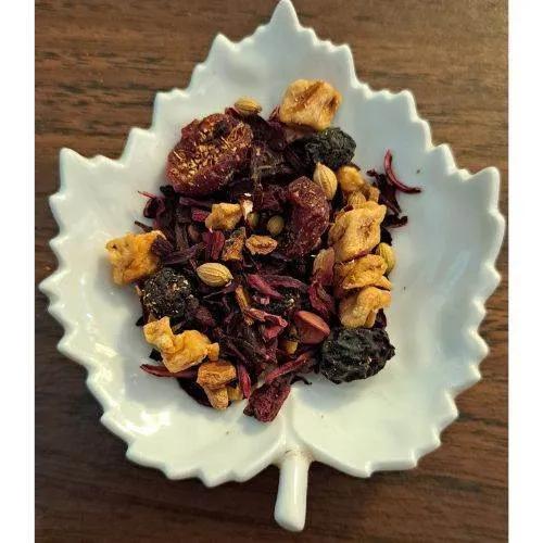 Homestead Fruit Chai herbs in a white leaf-shaped bowl on a wooden surface