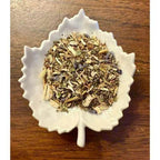 Migraine Relief Herbal mix in a white leaf-shaped bowl on a wooden surface