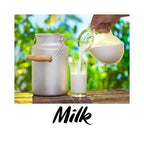 Milk being poured from a pitcher into a glass with a metal milk can, against a blurred green outdoor background.