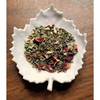 Mom's Morning Wellness herbs in a white ceramic dish on a wooden surface