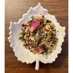 Moon Cycle Tea Herbal tea mix in a white leaf-shaped bowl on a wooden surface
