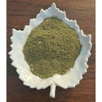 Nourishing Green Latte powder on a white leaf-shaped dish on a wooden surface