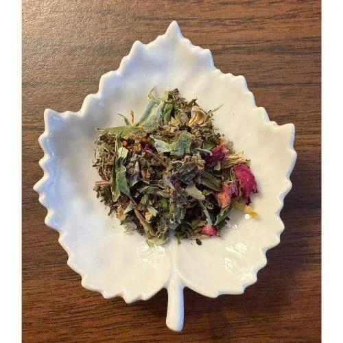 Nourishing Ice Tea Herbal mix in a white leaf-shaped bowl on a wooden surface