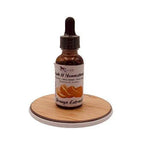 Bottle of orange extract on a wooden coaster with a white background