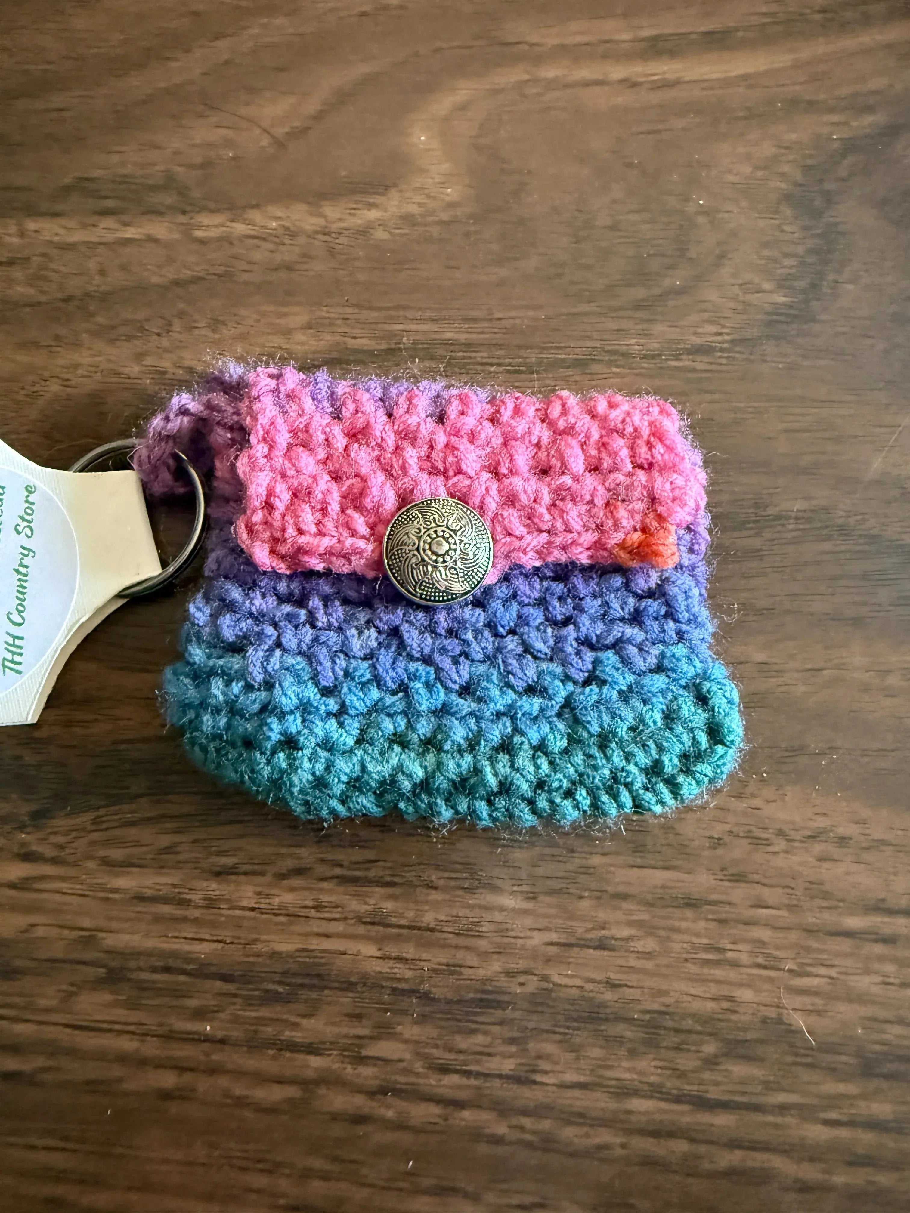 Colorful knitted pouch with a button on a wooden surface