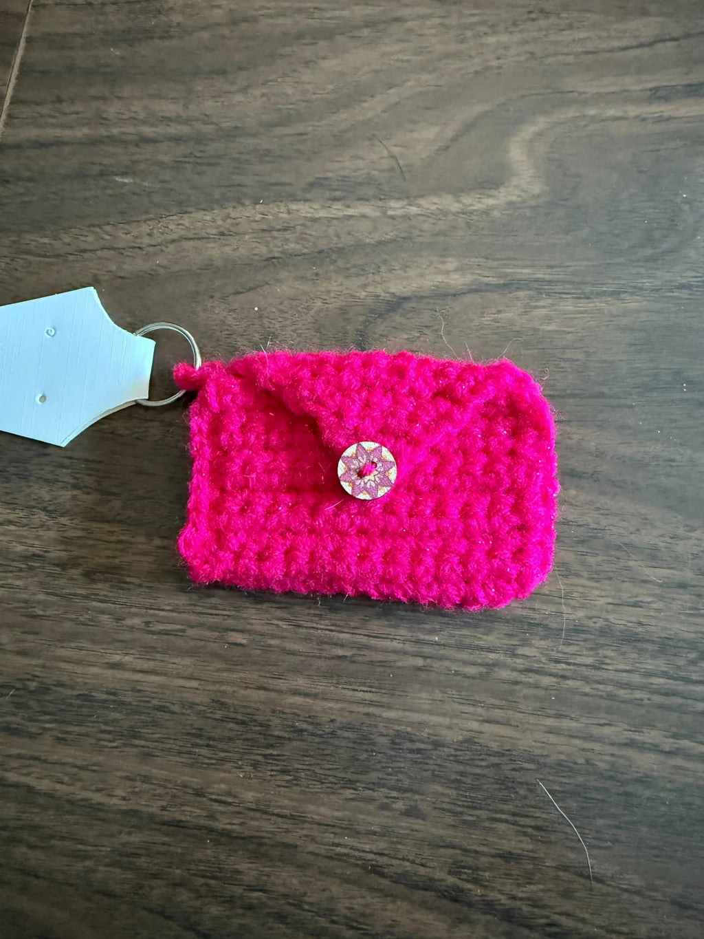 Pink crocheted pouch with a button on a wooden surface