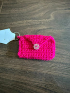 Pink crocheted pouch with a button on a wooden surface