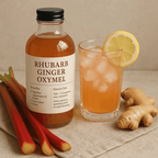 Bottle of rhubarb ginger oxymel with a glass of the drink, lemon, and ginger root on a neutral background.