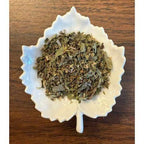 Shakespeare's Winter's Tale Tea in a white ceramic leaf-shaped bowl on a wooden surface