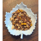White leaf-shaped bowl filled with Turmeric Tea on a wooden surface