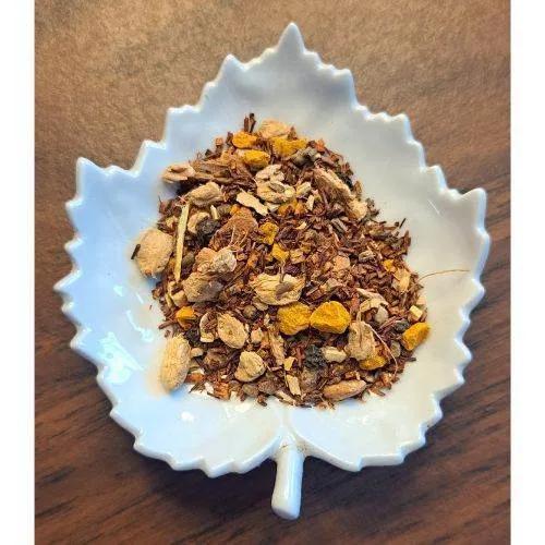 White leaf-shaped bowl filled with Turmeric Tea on a wooden surface