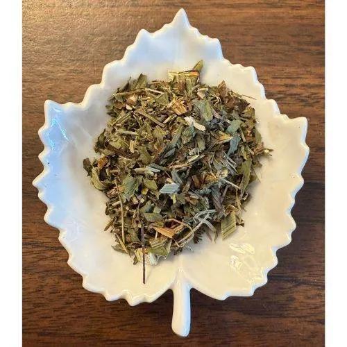 UTI Support Dry herbs in a white decorative bowl on a wooden surface