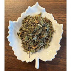 UTI Support Dry herbs in a white decorative bowl on a wooden surface