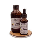 Two bottles of vanilla extract on a wooden coaster with a white background