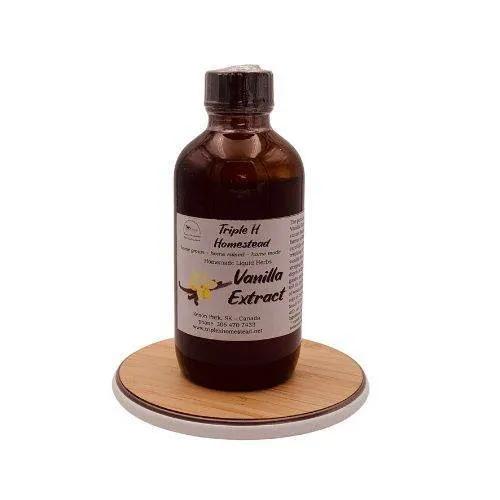 Bottle of vanilla extract on a wooden coaster with a white background