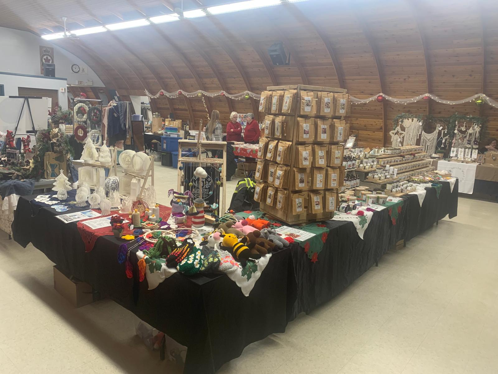 Indoor market or fair with tables displaying various items, including boxes and decorative objects.