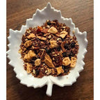 Winter Fireside Delight Herbal tea mix in a white leaf-shaped bowl on a wooden surface