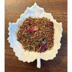 With Love Tea Herbal tea mix in a white leaf-shaped bowl on a wooden surface