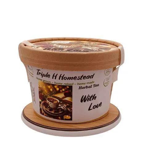 Container of Triple H Homestead herbal tea with a wooden lid and coaster on a white background